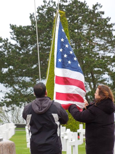 U.S. flag being raised above the graves at Normandy American Cemetery and Memorial